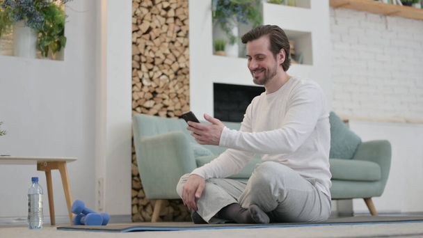Young Man Talking on Video Call on Laptop на сайті Yoga Mat - Фото, зображення
