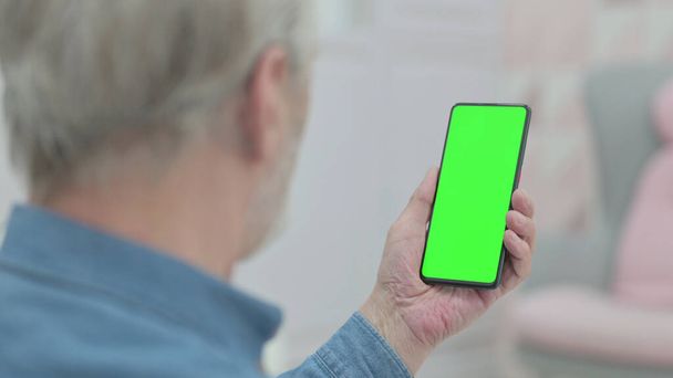 Οπίσθια όψη του γέρου κοιτάζοντας Smartphone με Chroma βασική οθόνη - Φωτογραφία, εικόνα