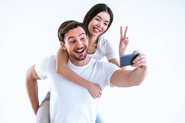 La feliz pareja haciendo una selfie sobre un fondo blanco - Foto, imagen