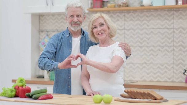 Vecchio coppia making cuore forma da mani mentre in cucina - Foto, immagini