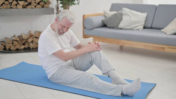 Öreg ember, akinek térd fájdalom a gyakorlaton matrac otthon - Fotó, kép
