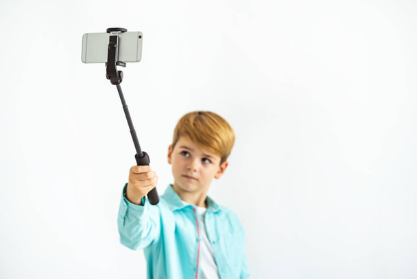 De jongen neemt een selfie op de witte achtergrond - Foto, afbeelding