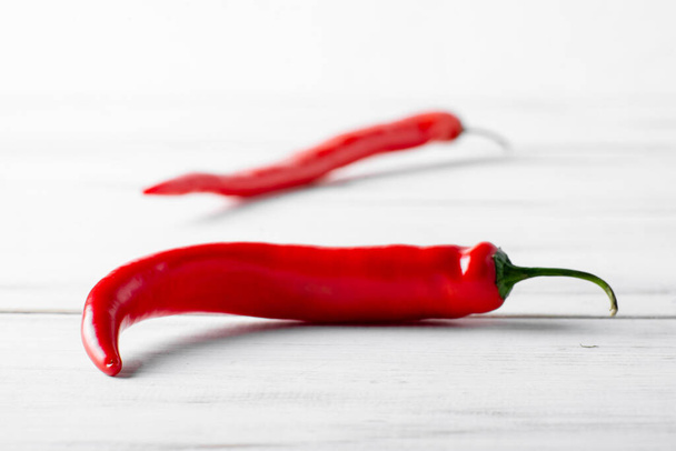 Red hot chili peppers on a white wooden background. - Foto, afbeelding