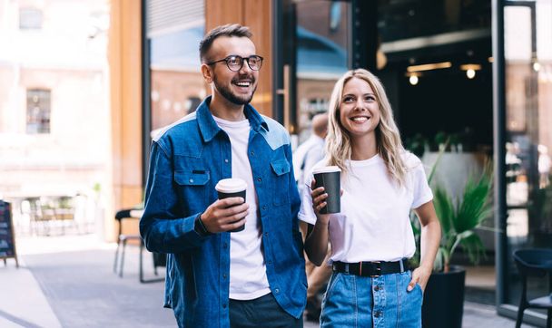 Young 20s caucasian male and female couple in love enjoying date talking to each other and holding coffee to go cup, cheerful woman and man friend resting and communicating on leisure weekends - Фото, зображення