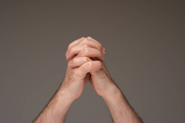 Кавказький самець молиться за руки. Студійні зйомки, ізольовані на коричневому фоні. - Фото, зображення