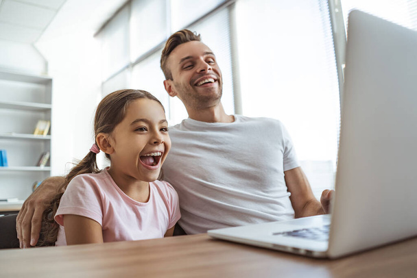 De gelukkige man en een meisje met een laptop aan het bureau - Foto, afbeelding