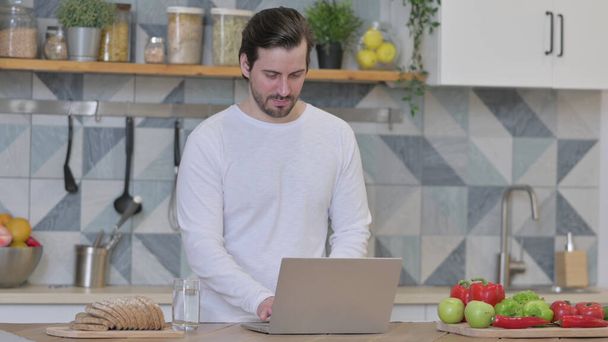 Young Man Working on Laptop in Kitchen - Photo, image