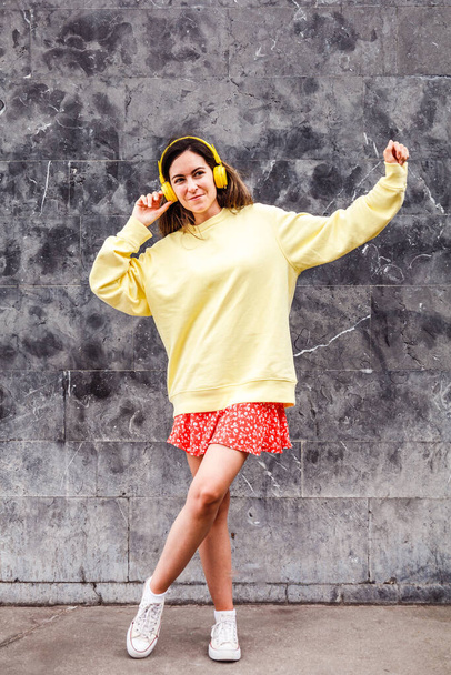 Young brunette woman dancing with a limp. Autumn outfit and headphones - Foto, immagini