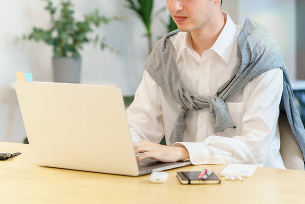 Close-up of a young man using a laptop in a casual space - Photo, Image