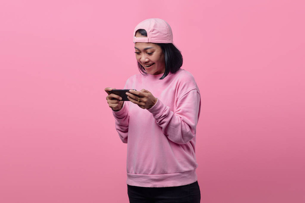 幸せな表情のスマートフォンでビデオゲームをプレイする美しいアジアの女性の肖像 - 写真・画像