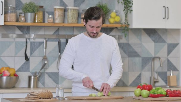 Healthy Young Man Cutting Vegetables in Kitchen - Fotografie, Obrázek