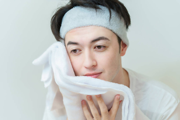 Asian young man wiping his face with a towel - Photo, Image