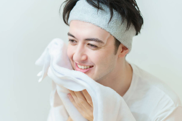 Asiatique jeune homme essuyant son visage avec une serviette - Photo, image