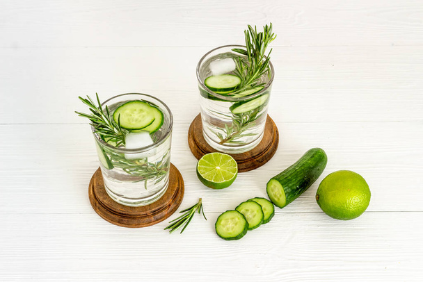 Cold fresh cocktail with lemon slices cucumber and rosemary - Photo, image