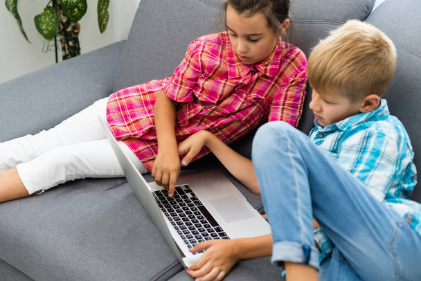 Cute children use laptop for education, online study, home studying, Boy and Girl have homework at distance learning. Lifestyle concept for home schooling. - Fotoğraf, Görsel