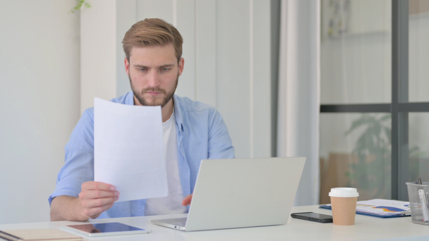 Mann mit Laptop liest Dokumente im Büro  - Foto, Bild