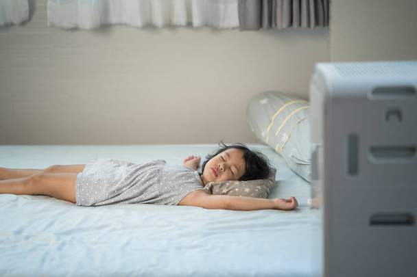 A sleeping girl next to the air purifier - 写真・画像