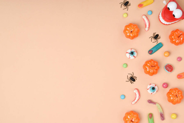 Various sweets on an orange background with a place for text. Background for the Halloween holiday. Flat layout, top view, a place to copy. - 写真・画像