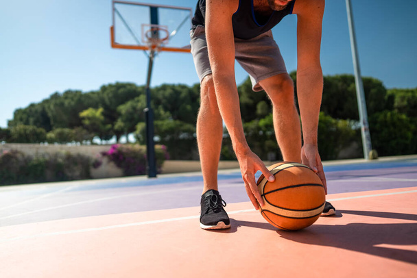 遊び場のバスケットボール選手は地面からボールを拾う - 写真・画像