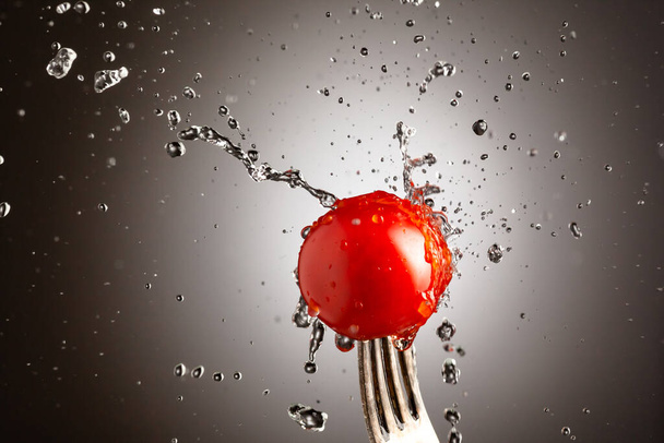 tomato cherry on a fork in splashes of water. Black white background - Foto, immagini