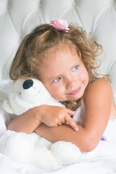 Cute baby girl with teddy bear in white bed - Zdjęcie, obraz