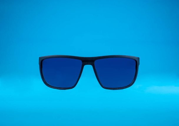 Sun Glasses with blue glass and black frame on blue background - Photo, Image