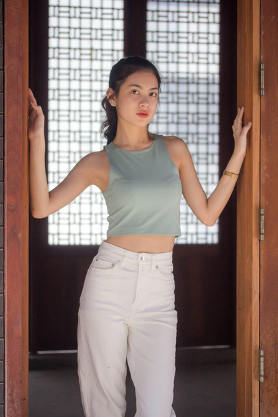 Retrato de tailandés china adulto hermosa chica verde camisa blanca jeans relajarse y sonreír - Foto, imagen
