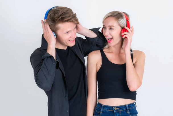 若いカップルの男と美しい女性は、白い背景に隔離された音楽を聴くためにヘッドフォンを身に着けています – 愛の生活カップルのコンセプト - 写真・画像