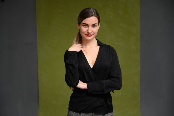 girl with makeup in a black jacket smiling on a dark green background - Фото, изображение