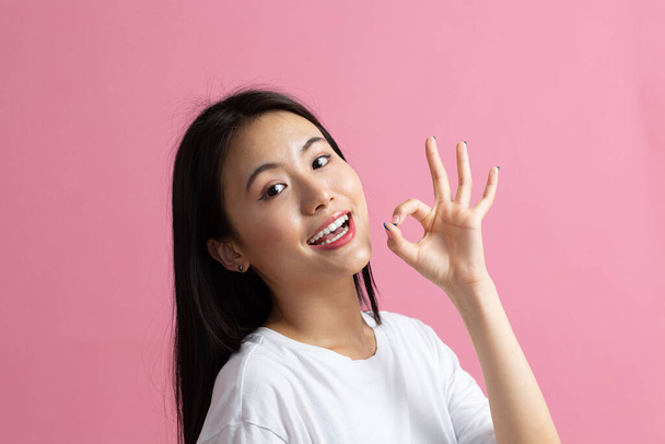 Porträt eines lächelnden asiatischen Mädchens mit Ok-Geste - Foto, Bild
