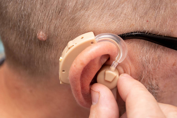 Egy férfi modern digitális hallókészüléket használ.. - Fotó, kép