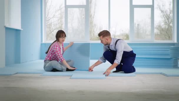 mester férfi együtt mosolygós nő szigetelt padló kiterjesztett polisztirol szóló laminált javítás során beltéri építési területen, adj nekem öt - Felvétel, videó