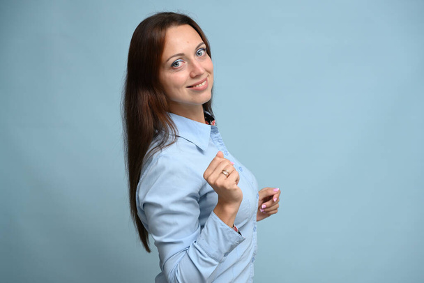 young woman in a blue shirt with a smile stands on a blue background - Foto, immagini