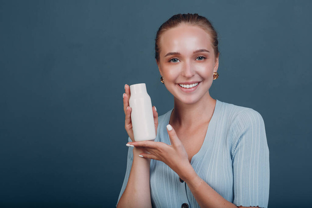 Hezká mladá žena drží láhev s prázdným prostorem. Šampon a kondicionér. - Fotografie, Obrázek
