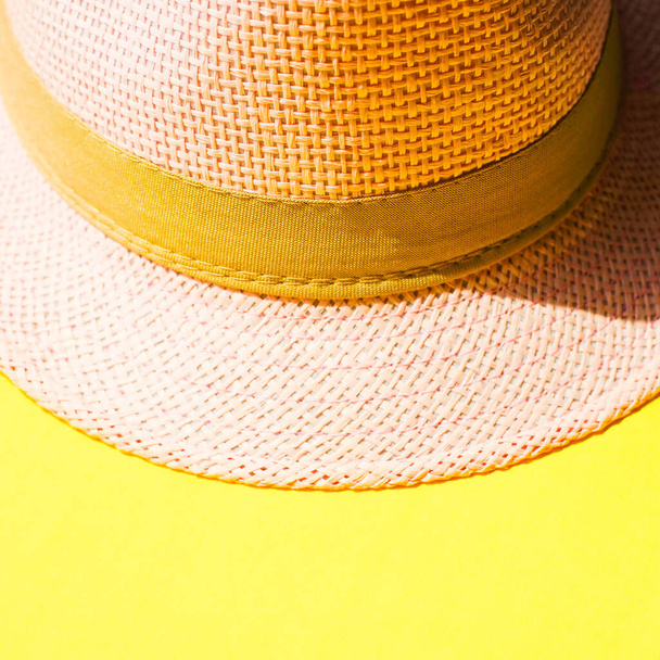 Lichtroze vrouwelijke hoed op levendige zonnige gele tafel. - Foto, afbeelding