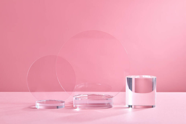 Glas Geometrische podium voor product display. Monochroom platform met geribbelde acryl platen en kristallen driehoek op roze achtergrond. Stijlvolle achtergrond voor presentatie. Minimale stijl - Foto, afbeelding