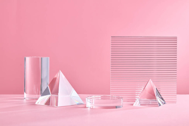 podium géométrique en verre pour l'affichage du produit. Plate-forme monochrome avec des feuilles d'acrylique nervurées et triangle de cristal sur fond rose. Contexte élégant pour la présentation. Style minimal - Photo, image