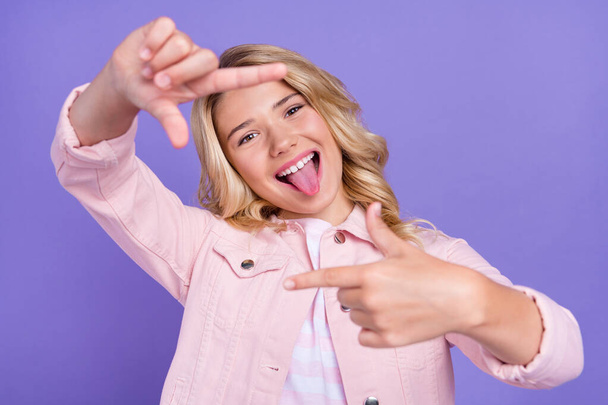 Portrait of positive carefree teen tongue out arms make frame symbol isolated on violet color background - Foto, Imagem