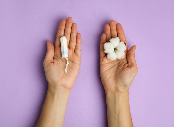Top view of woman holding tampon and cotton flower on lilac background, closeup - Fotografie, Obrázek