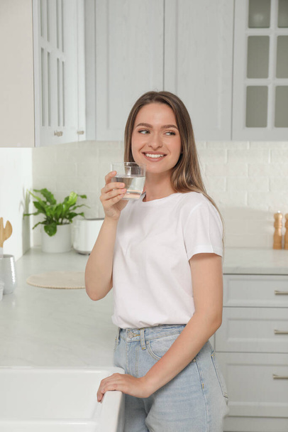 Woman drinking tap water from glass in kitchen - Foto, Imagem