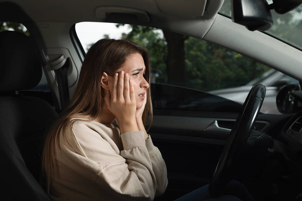 Στρεσαρισμένη νεαρή γυναίκα στη θέση του οδηγού του σύγχρονου αυτοκινήτου - Φωτογραφία, εικόνα