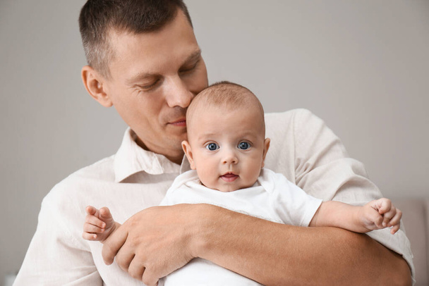 Happy father holding his cute baby on grey background - Foto, Bild