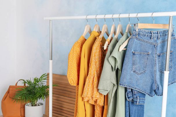 Rack with stylish clothes near light blue wall indoors - Photo, Image