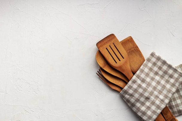 Set de utensilios de cocina de madera en una servilleta a cuadros sobre fondo gris neutro. Copiar espacio - Foto, imagen