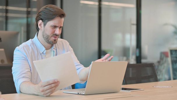 Man with Laptop having Loss Reading Documents  - Foto, Imagem