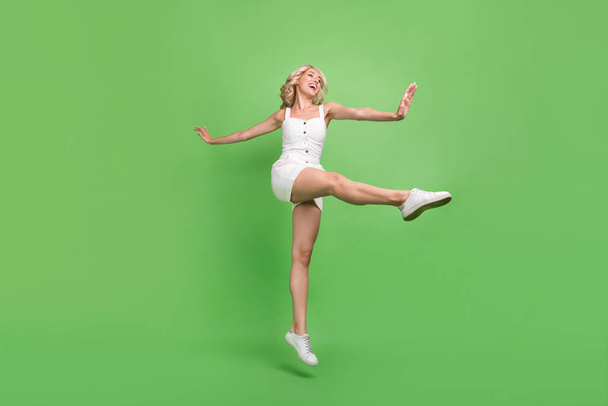 Full size photo of funky funny energetic sportive girl dancing stretching legs isolated on green color background - Φωτογραφία, εικόνα