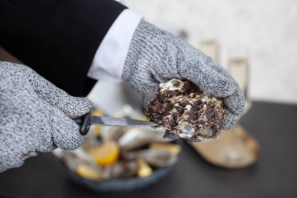 Hands of waiter in special gloves opening an oyster - Valokuva, kuva