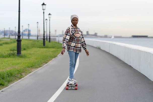 Fille africaine souriante sur skateboard. Happy skateboarder femelle profiter du longboard au début du printemps. - Photo, image