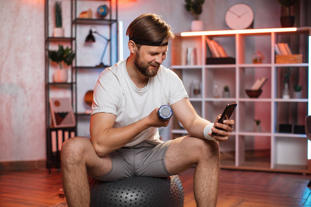 Man wathching online tutorial on mobile during home sport - Fotoğraf, Görsel