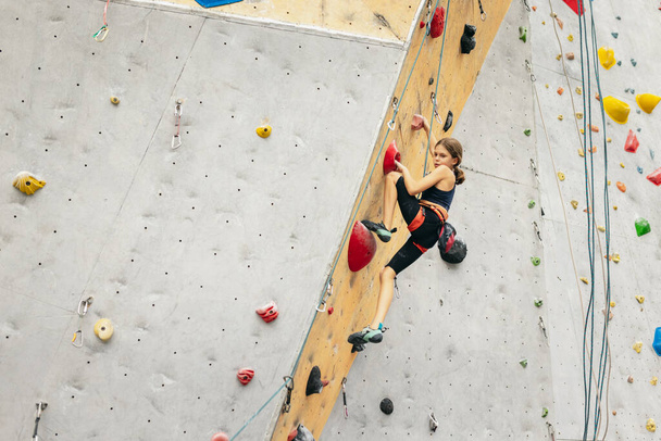 Una ragazza carina adolescente che pratica sulla parete rocciosa nel centro di arrampicata. Concetto di stile di vita sportivo, attività, infanzia felice - Foto, immagini